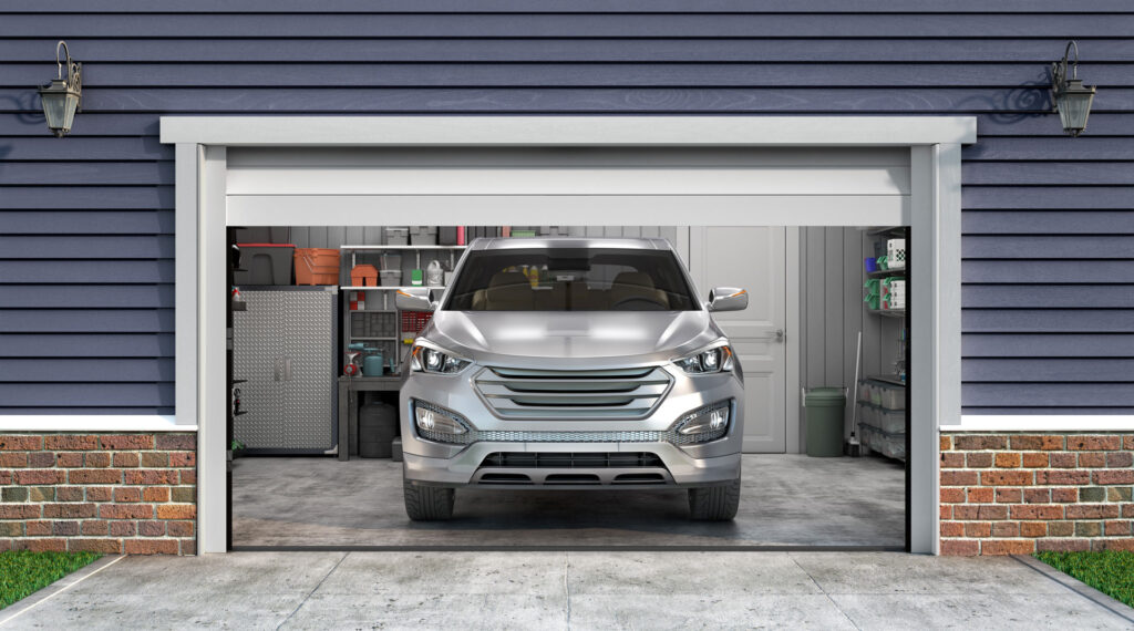 A modern silver SUV parked inside a clean garage with organized shelves and storage items visible. The garage features a blue siding exterior with white trim and a brick base, reflecting a tidy and well-maintained residential setting.