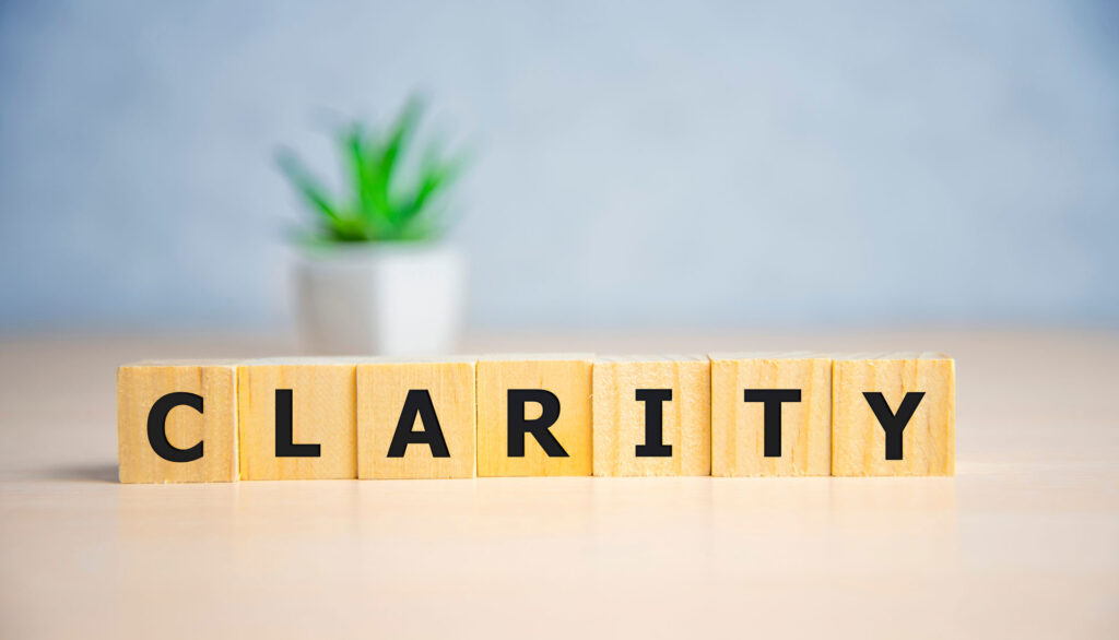 The word 'CLARITY' spelled out with bold black letters on square wooden blocks, perhaps referencing the clarity or transparency of epoxy topcoats for concrete surfaces.