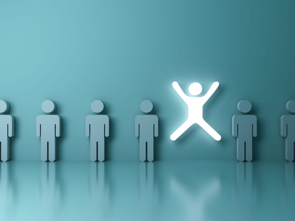 A conceptual illustration showing a row of identical grey figures and one figure in the center glowing and standing out with arms raised, on a smooth teal background. This image represents individuality, creativity, standing out from the crowd, or leadership concepts.