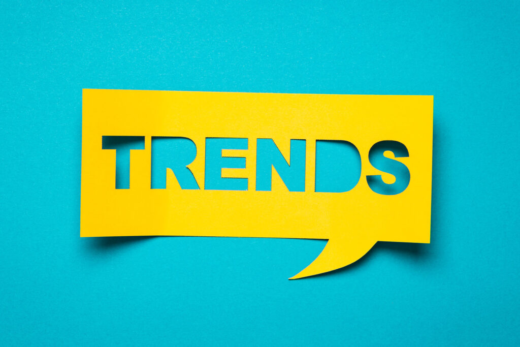 A bold yellow speech bubble cut-out with the word 'TRENDS' in capital letters on a bright turquoise background. The design is simple yet eye-catching, symbolizing trending topics or current popular discussions, ideal for use in articles or sections related to fashion, technology, or social media trends.